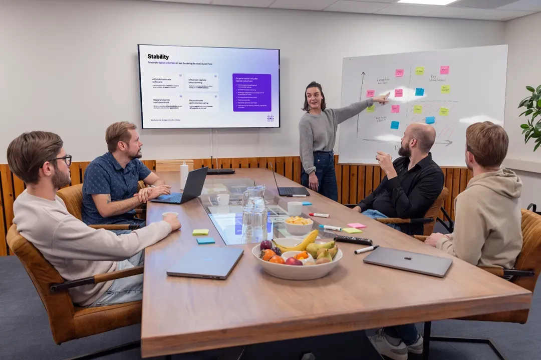 Het team van Hatch in overleg aan de grote tafel, met whiteboard en scherm
